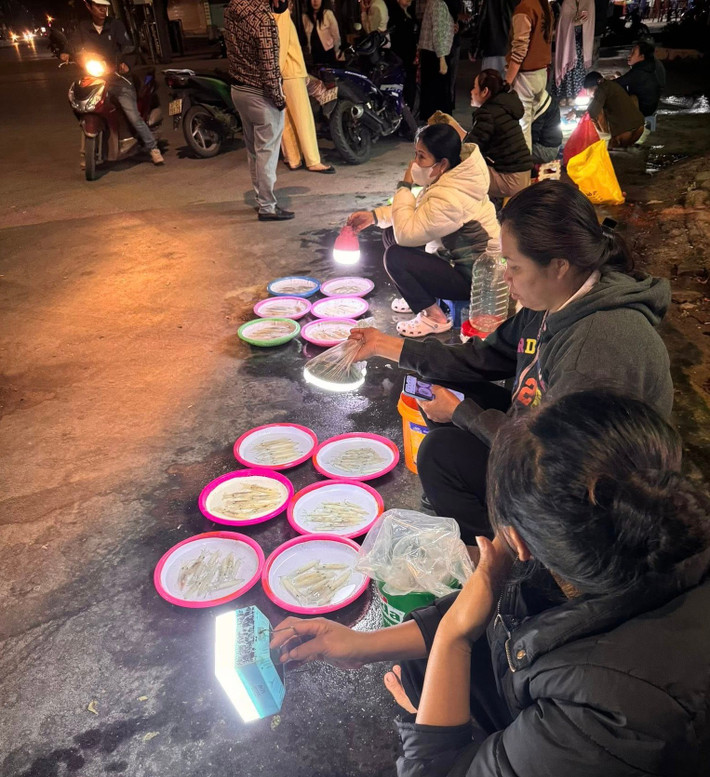 Chẳng cần biển hiệu hay gian hàng, người bán chỉ cần một góc vỉa hè, vài chậu mực vừa được đưa từ biển lên cùng chiếc đèn pin cầm tay. Ánh sáng yếu ớt ấy lại vô tình làm nổi bật những con mực đang phát sáng lấp lánh, thu hút ánh nhìn của bất kỳ ai đi ngang qua. Ảnh Nghệ An News
