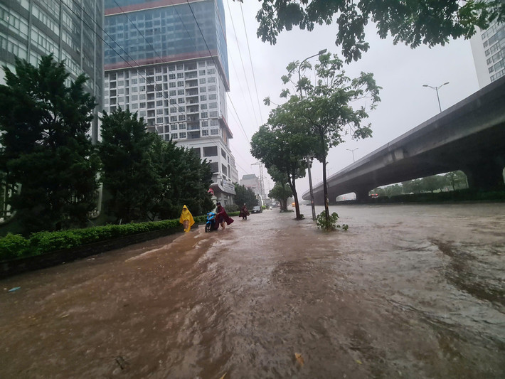 Đường Phạm Hùng ngập sâu, người dân phải dắt bộ xe trên vỉa hè.