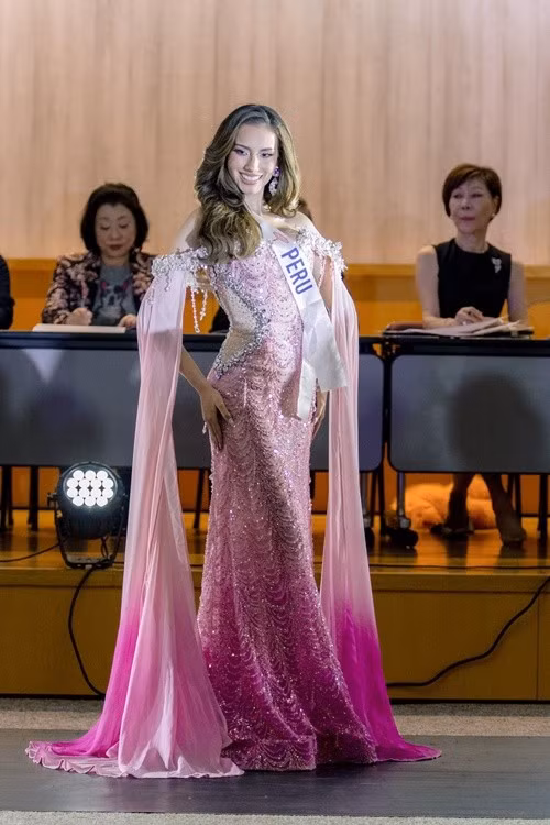 Đại diện Peru - Nathie Quijano nổi bật với đầm dạ hội tông hồng, ôm sát thân trên và xòe nhẹ ở chân váy, tà áo dài đầy thướt tha. Ảnh: Miss International.
