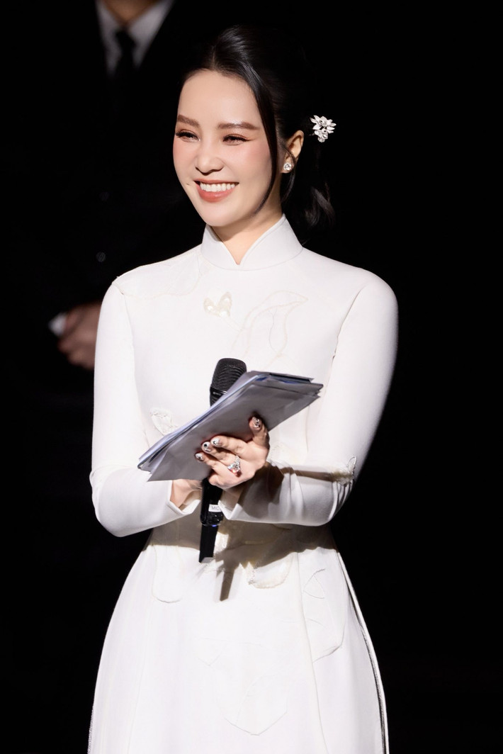 Thụy Vân diện áo dài trắng làm MC. Mẫu áo dài có phom dáng gọn gàng cùng gam màu tinh khôi không chỉ tôn vẻ đẹp nền nã của nàng hậu mà còn phù hợp với tính chất trang trọng của chương trình.