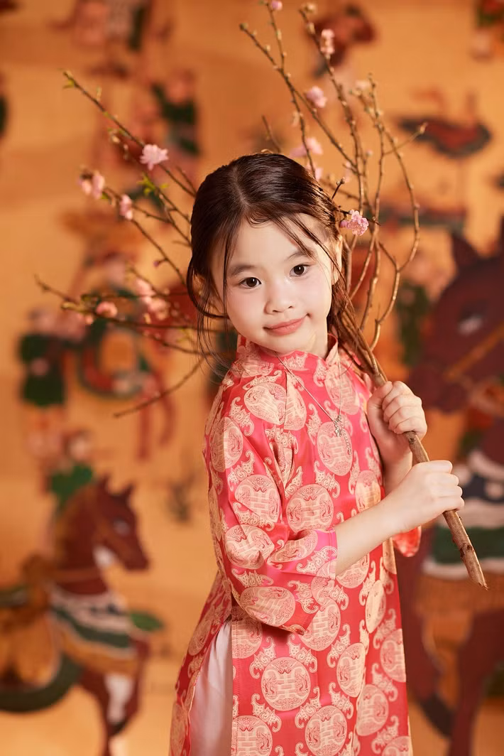 Trong khung hình đầu xuân, ái nữ nhà Tú Vi – Văn Anh tay cầm cành hoa đào, toát lên vẻ hồn nhiên, ấm áp đúng tinh thần sum vầy ngày Tết. Ảnh: FB Tú Vi.