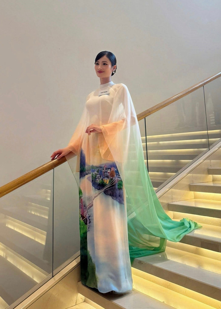 Ý Nhi nói thêm: “Điểm độc đáo và đầy ý nghĩa chính là hình ảnh sông Hằng, một biểu tượng văn hóa thiêng liêng và trù phú của Ấn Độ, được vẽ thủ công một cách sống động và tinh tế. Sự kết hợp hài hoà giữa các gam màu xanh lá, trắng và cam không chỉ tạo nên vẻ nhẹ nhàng, thanh lịch mà còn là sự liên kết ý nhị với màu sắc trên quốc kỳ Ấn Độ. Bên cạnh tôn vinh vẻ đẹp Ấn Độ, chiếc áo dài còn thể hiện sự giao thoa văn hóa sâu sắc giữa hai quốc gia đồng thời gửi gắm sự trân trọng và tình cảm của Ý Nhi cũng như NTK Trung Đinh đối với đất nước, con người nơi đây”. Ảnh: FB Ý Nhi.