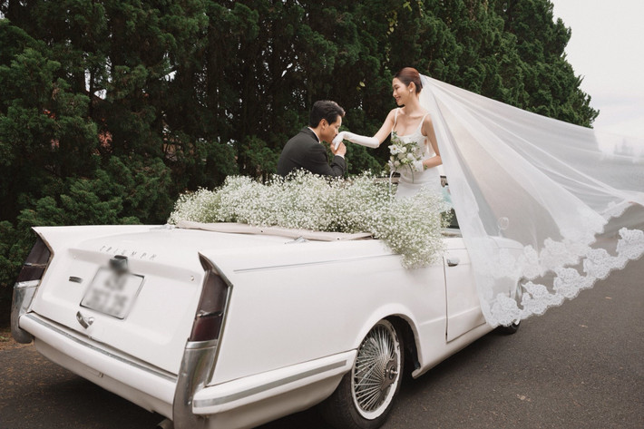 Đôi uyên ương tạo dáng trên chiếc xe mui trần cổ điển.