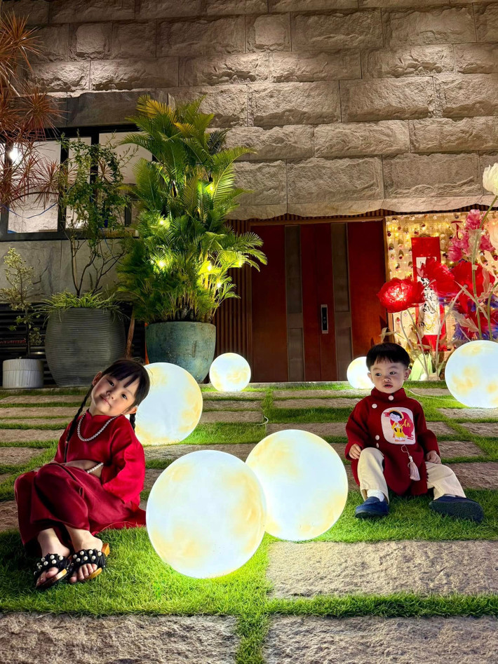 Bé Suchin diện áo dài đỏ truyền thống, phom dáng rộng rãi, kết hợp các phụ kiện nhỏ xinh như vòng cổ, dép đính hạt. Ảnh: Instagram Suchin - Sutin.