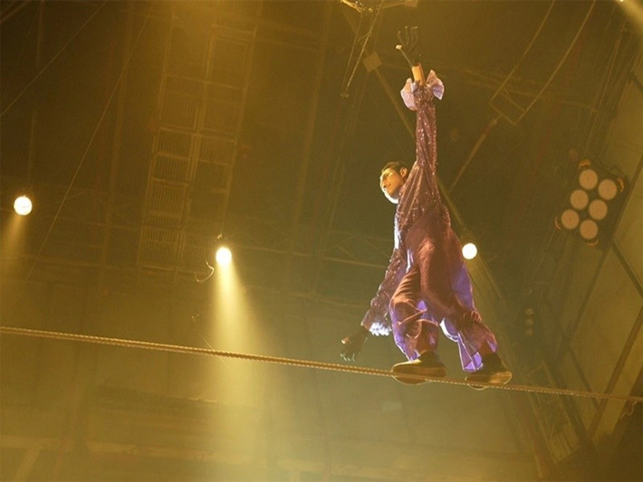 Kiều Minh Tuấn phải gồng toàn thân để giữ thăng bằng khi một diễn viên khác đứng trên vai mình ở trên dây. Dụng cụ hỗ trợ và dây an toàn chỉ gánh được 30% trọng lượng, còn 70% sức nặng do Kiều Minh Tuấn phải tự gánh.Ảnh: VOV.