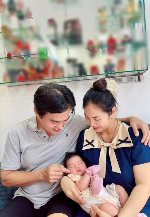 Hình ảnh vợ chồng Cao Minh Đạt cùng cúi xuống ngắm con ngủ, ánh nhìn trìu mến dành cho con, tạo nên một bức tranh gia đình giản dị mà ấm áp.