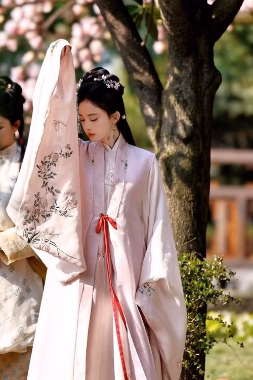 Chỉ dùng tay áo che nắng, mỹ nhân Tân Cương cũng tạo nên khoảnh khắc đẹp như tranh. Theo Tiền Phong, nhà sản xuất Vu Chính đã khéo léo chọn cho Cổ Lực Na Trát tạo hình không rườm rà nhiều chi tiết, trang phục đều có màu sắc ngọt ngào thanh nhã càng tôn lên khí chất kiêu sa của cô ở dự án phim Ngọc Minh Trà Cốt năm 2025. Ảnh: Tiền Phong.