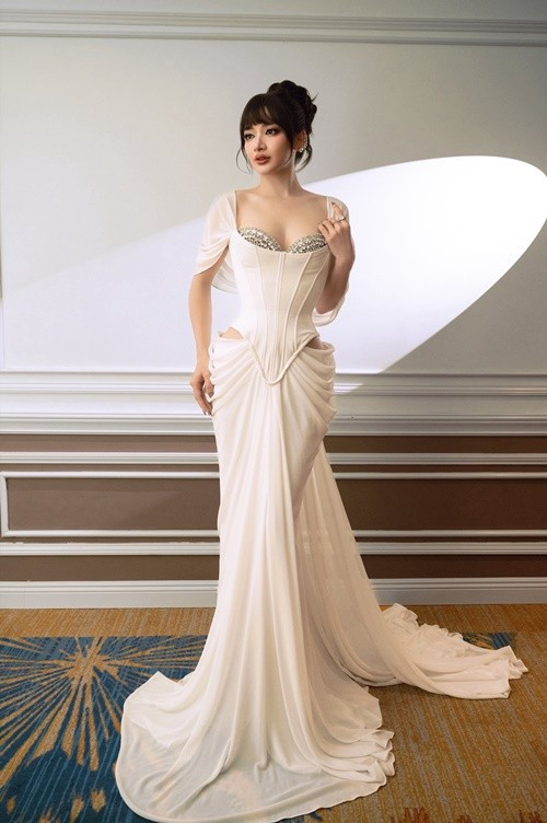 Đinh Y Quyên xuất hiện với vẻ đẹp kiêu sa, sang trọng đậm chất thảm đỏ, dễ dàng thu hút mọi ánh nhìn ngay từ khoảnh khắc đầu tiên. Cô diện váy dạ hội trắng ôm sát, phom corset tôn trọn vòng eo thon gọn và đường cong mềm mại, phần ngực đính đá lấp lánh tạo điểm nhấn vừa gợi cảm vừa tinh tế. Chất liệu váy rũ nhẹ, tà dài quét sàn mang lại cảm giác nữ tính, quyền lực nhưng vẫn rất thanh thoát. Ảnh: FB Y Quyên.