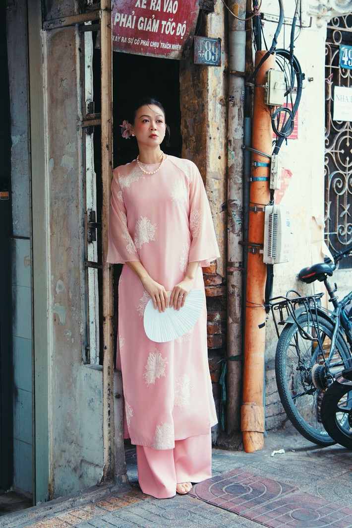 Siêu mẫu Ngọc Nga diện áo dài cách tân màu hồng phấn, kết hợp chuỗi ngọc trai và quạt giấy trắng, gợi hình ảnh người phụ nữ Việt xưa đầy thanh tao, hoài niệm. Ảnh: FB Ngọc Nga.