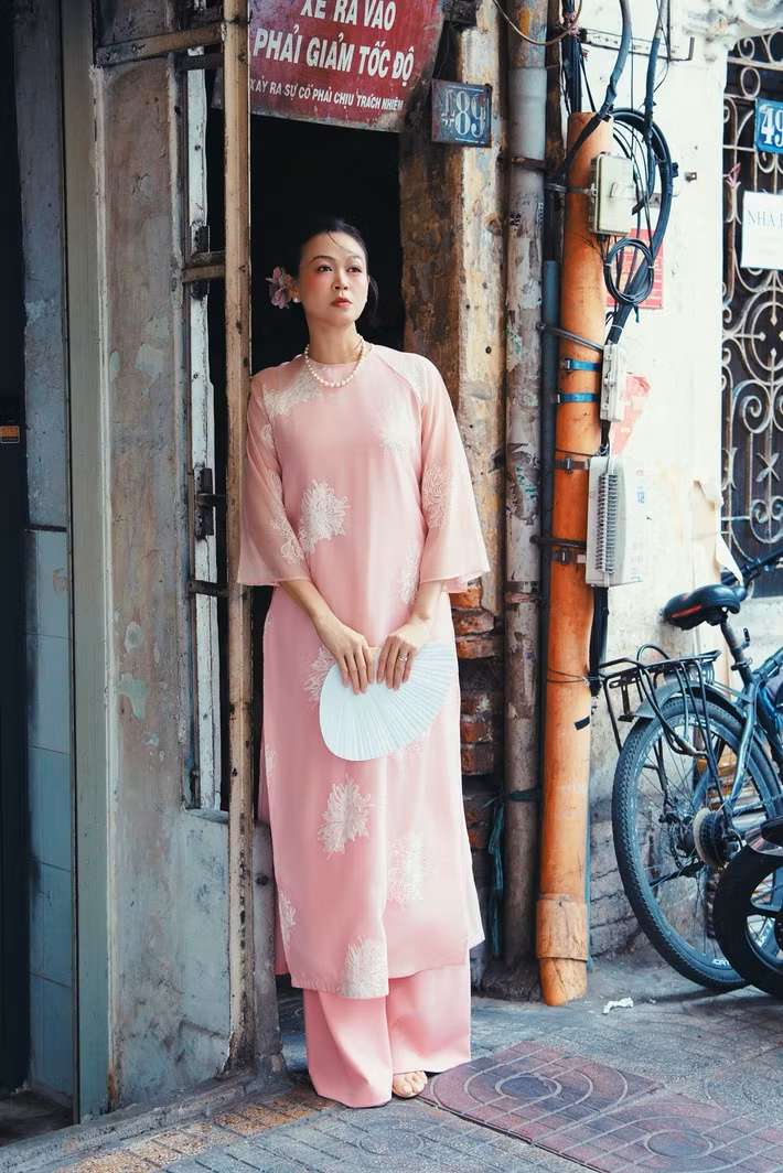 Siêu mẫu Ngọc Nga diện áo dài cách tân màu hồng phấn, kết hợp chuỗi ngọc trai và quạt giấy trắng, gợi hình ảnh người phụ nữ Việt xưa đầy thanh tao, hoài niệm. Ảnh: FB Ngọc Nga.