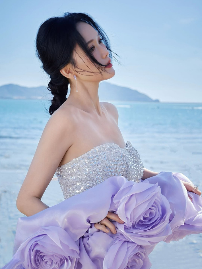 Trong bộ ảnh mới, Trần Kiều Ân diện váy quây dáng đuôi cá ôm sát, được đính kết đá và hạt cườm lấp lánh màu bạc, dải lụa màu tím quấn quanh eo và tay, tạo thành những bông hoa.