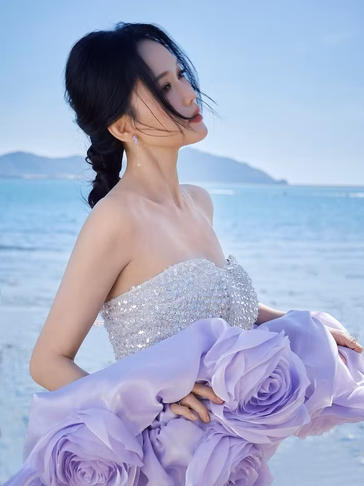 Trong bộ ảnh mới, Trần Kiều Ân diện váy quây dáng đuôi cá ôm sát, được đính kết đá và hạt cườm lấp lánh màu bạc, dải lụa màu tím quấn quanh eo và tay, tạo thành những bông hoa.