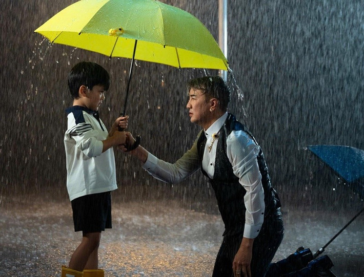 Trong MV, bé Polo che ô cho bố trong cơn mưa tầm tã. Đàm Vĩnh Hưng chia sẻ trên Pháp Luật TPH CM, ban đầu, anh chọn hình ảnh người mẹ, người phụ nữ để xuất hiện trong MV, nhưng cuối cùng con trai lại xuất hiện, bởi với anh, bé Polo là người gần gũi, là động lực động viên anh trong những ngày “bão tố”. Ảnh: FB Polo Huỳnh.