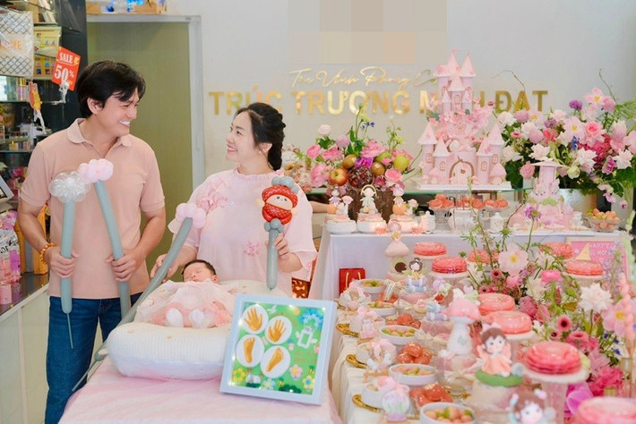 Bữa tiệc đầy tháng của bé Dâu Tây được vợ chồng Cao Minh Đạt chuẩn bị chỉn chu với không gian trang trí tông hồng chủ đạo, điểm xuyết hoa tươi và bánh kem tạo hình lâu đài cổ tích, mang đậm không khí ấm áp của một buổi sum họp gia đình.