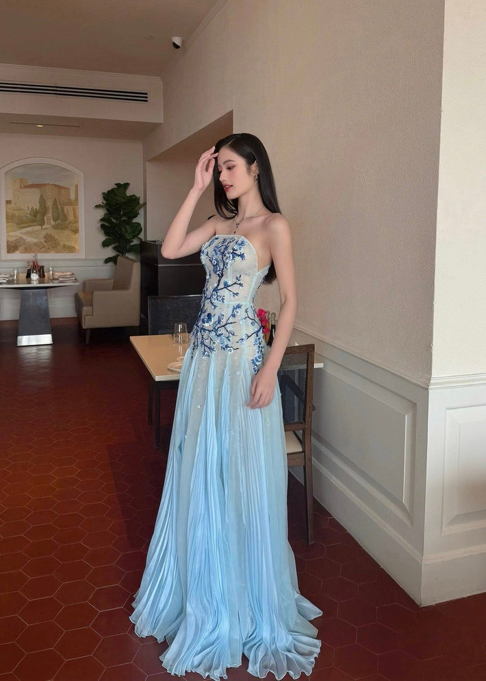 Ngày thứ 12 ở Miss World 2025, Hoa hậu Ý Nhi diện chiếc váy xanh. Lấy cảm hứng từ họa tiết truyền thống trên gốm hoa lam – dòng gốm cổ nổi tiếng của Việt Nam, bộ trang phục tái hiện hình ảnh hoa lá, chim muông quen thuộc qua kỹ thuật thêu tay và đính kết thủ công trên nền vải voan mềm mại, tạo nên một tổng thể thanh thoát, hài hòa và đầy nghệ thuật. Ảnh: FB Ý Nhi.