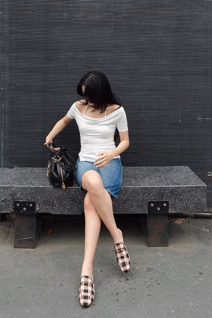 Với áo trắng trễ vai và chân váy denim, Hoàng Thùy Linh ưu tiên cách phối đơn giản. Túi da đen và loafer họa tiết giúp bộ đồ đường phố bớt đơn điệu.