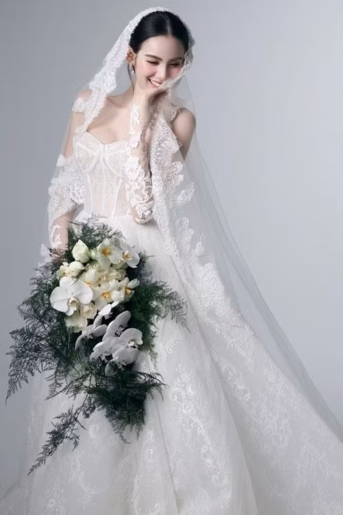 Hương Liên trang điểm tông màu cam nhạt, làm nổi bật gương mặt thanh tú. Cô chọn mẫu váy cưới ren trắng, nổi bật với chi tiết corset cúp ngực tôn dáng. Ảnh: Instagram Hương Liên.