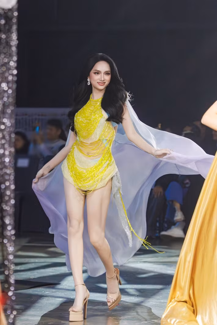 Hương Giang xuất hiện nổi bật với bộ trang phục ôm sát tông vàng chanh đính tua rua ánh kim. Phần khăn voan tím bay phía sau giúp tổng thể thêm mềm mại, đồng thời tạo hiệu ứng chuyển động bắt mắt trên sân khấu. Mái tóc xoăn sóng lớn cùng lối trang điểm sắc sảo giúp cô giữ được vẻ quyến rũ nhưng vẫn sang trọng.