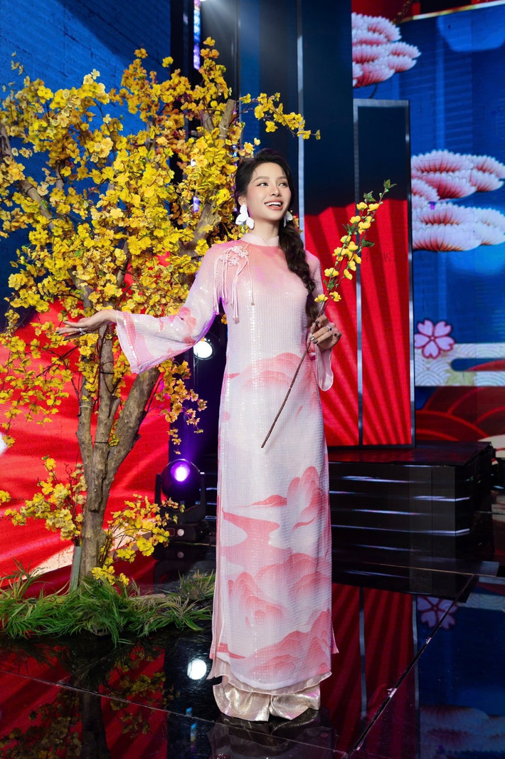 Nữ ca sĩ diện áo dài tông trắng – hồng nhẹ nhàng, điểm nhấn là họa tiết mây núi cách điệu trên tà áo. Kiểu tóc tết lệch cùng hoa tai bản lớn mang đến sự giao thoa giữa truyền thống và hiện đại. Ảnh: FB Phương Trinh Jolie.