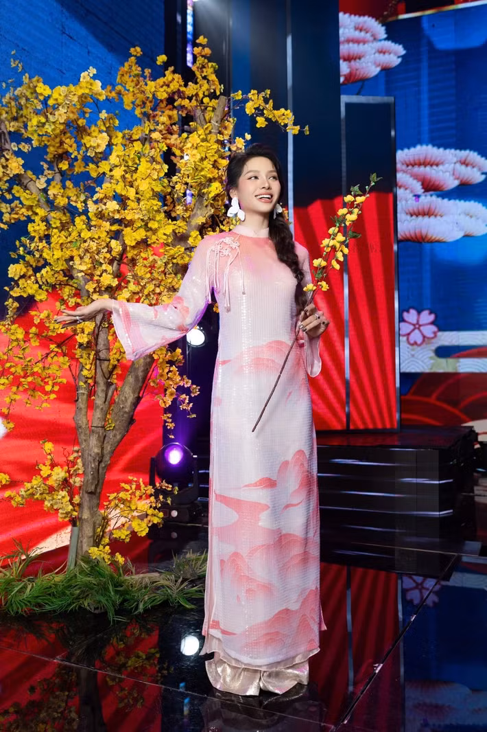 Nữ ca sĩ diện áo dài tông trắng – hồng nhẹ nhàng, điểm nhấn là họa tiết mây núi cách điệu trên tà áo. Kiểu tóc tết lệch cùng hoa tai bản lớn mang đến sự giao thoa giữa truyền thống và hiện đại. Ảnh: FB Phương Trinh Jolie.