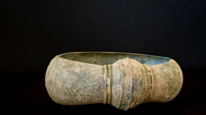 Chiếc vòng tay có thành dày và mặt cắt ngang hình bầu dục, với các đường gờ ngang song song tạo hiệu ứng chạm nổi. Bề mặt bên ngoài được phủ một lớp gỉ màu nâu xanh do quá trình oxy hóa đồng, dấu hiệu của sự tiếp xúc lâu dài với đất, trong khi mặt trong nhẵn mịn, rõ ràng được thiết kế để tạo sự thoải mái cho người đeo. Ảnh: @Hiệp hội Kociewskie Poszukiwacze.