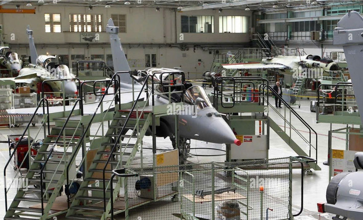 Tiêm kích Dassault Rafale đang được bảo dưỡng, lắp ráp trong nhà xưởng kỹ thuật, với các bệ công tác bao quanh thân máy bay để kỹ thuật viên kiểm tra và hoàn thiện hệ thống trước khi bàn giao.
