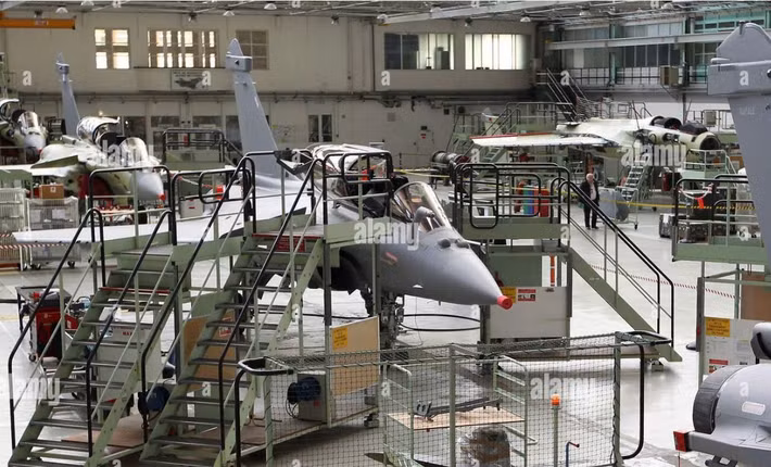 Tiêm kích Dassault Rafale đang được bảo dưỡng, lắp ráp trong nhà xưởng kỹ thuật, với các bệ công tác bao quanh thân máy bay để kỹ thuật viên kiểm tra và hoàn thiện hệ thống trước khi bàn giao.