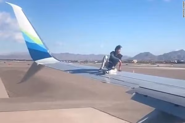 Hi huu, mot nguoi dan ong leo len canh may bay sap khoi hanh