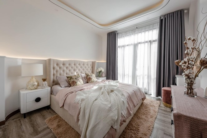 Một chiếc giường màu trắng kem kết hợp tủ đầu giường màu trắng vừa phù hợp cho độ tuổi vừa tạo cảm giác sang trọng cho căn phòng. Cửa kính lớn với rèm màu trắng đi liền mạch thiết kế và giảm độ chói cho căn phòng