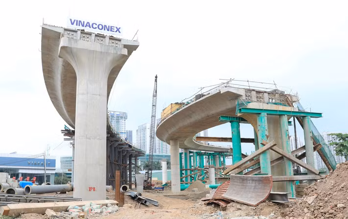 Trên công trường, máy móc hoạt động nhộn nhịp; hệ thống khung thép phục vụ thi công hầm chui và cầu dẫn được lắp dựng đồng bộ, tạo nên không khí thi công khẩn trương.