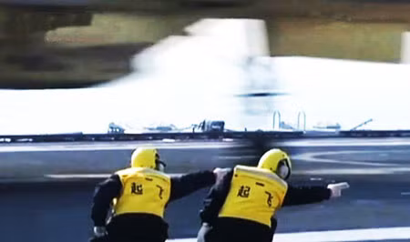 Trong đó, đặc biệt là 2 thủy thủ trên tàu Liêu Ninh, mặc bộ đồ màu vàng tươi, đội mũ bảo hiểm, quay lưng về phía máy quay và cúi người trong khi tay phải duỗi thẳng chỉ hướng cho một chiếc chiến đấu cơ J-15 lần đầu được gọi là “Tàu sân bay Style” được rất nhiều người bắt chước.