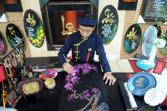Và cả vẽ tranh hoa đào bán cho khách tham quan.