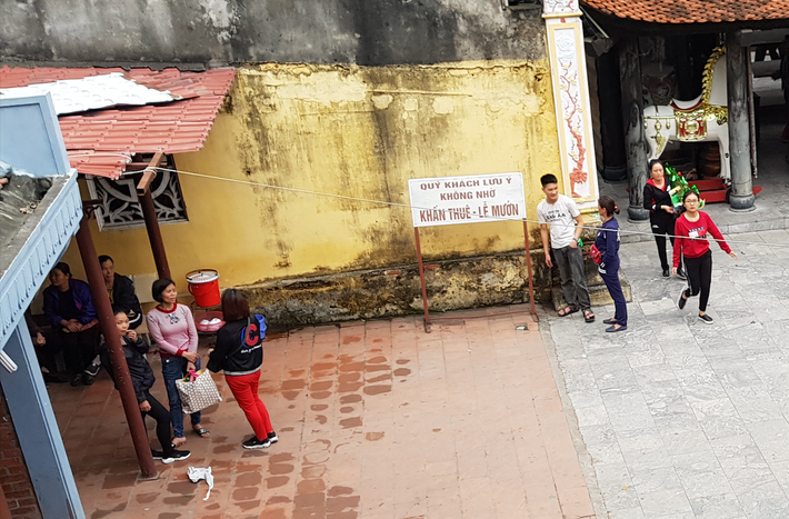 Mặc dù Ban quản lý đền Bà Chúa Kho đã có biển khuyến cáo người dân không sử dụng dịch vụ khấn thuê - lễ mướn hộ. Thế nhưng, những người làm dịch vụ này vẫn ngang nhiên hoạt động. Họ thường tụ tập ngay từ cổng đền và khu vực sân để chào mời khách. (Ảnh: Trọng Nghĩa)