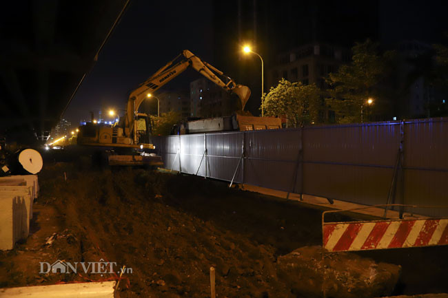 Đơn vị thi công tập trung hơn chục máy cẩu, máy xúc, xe lu, xe ủi ở gầm cầu cạn để xén thảm cỏ, hạ thấp cốt đường vào buổi tối. Dự kiến, mỗi bên thảm cỏ được xén từ 1,5 m đến 3,5 m.