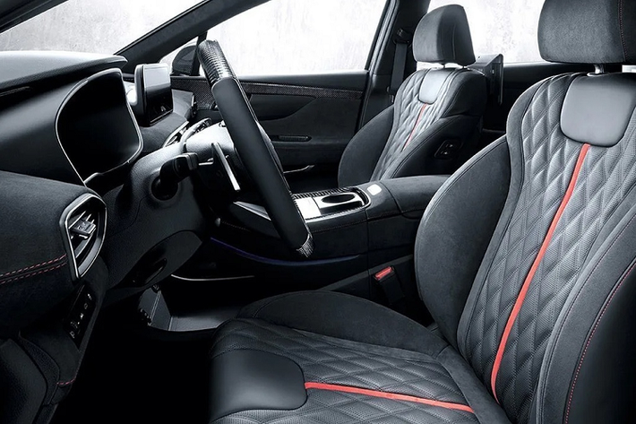 Với gói nâng cấp N-Performance, nội thất của Hyundai SantaFe thay đổi hoàn toàn, từ thiết kế sang trọng cao cấp chuyển sang phong cách thể thao mạnh mẽ. Cabin được bọc da Alcantara khâu chỉ đỏ đi cùng nhiều chi tiết trang trí ốp carbon ở bảng tablo, vô-lăng, viền cửa hay phía sau lưng ghế.