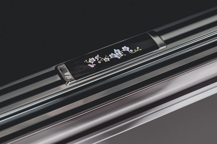 Vì đây là một chiếc Phantom duy nhất nên quá trình cá nhân hóa không chỉ dừng lại ở ở khu vực táp lô. Hai chi tiết đặc biệt khác được nhà thiết kế Yohan Benchetrit của Rolls-Royce Bespoke tạo nên là bàn ăn và bệ bước chân mang họa tiết phong lan trên lớp gỗ ốp màu đen piano black.