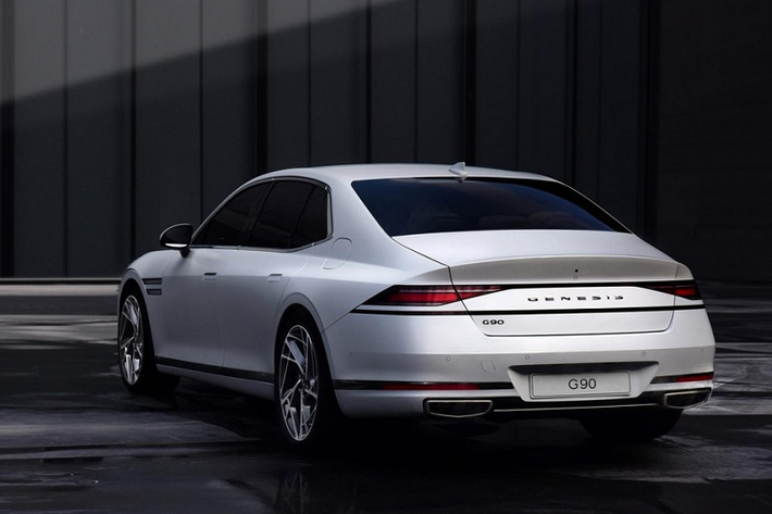 Thật bất ngờ khi Genesis G90 2022 không được trang bị cụm đèn hậu với 2 dải đèn LED song song giống trên đầu xe. Thay vào đó, mẫu sedan hạng sang này đi kèm cụm đèn hậu LED thanh mảnh và góc cạnh, nối liền với nhau. Bên dưới là một dải đèn nữa, kéo dài sang chắn bùn sau khiến đuôi xe trông như rộng hơn.