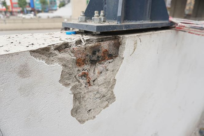 Tường bị nứt vỡ chưa được sửa chữa khi các công nhân thi công cột chống mái hành lang đi bộ.