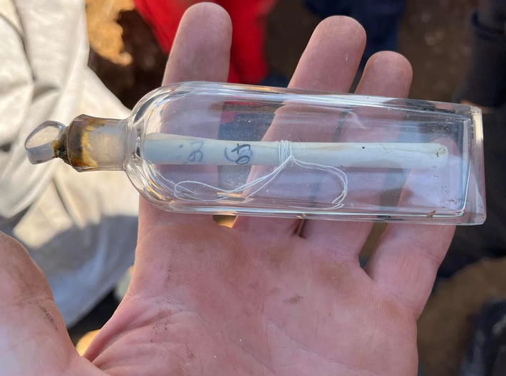 Không chỉ có vậy, các chuyên gia khảo cổ tình nguyện còn phát hiện ra một thông điệp 200 năm tuổi được niêm phong trong một chai thủy tinh, giấu bên trong một chiếc bình đất sét cùng với hai đồng xu. Ảnh: @Guillaume Blondel.