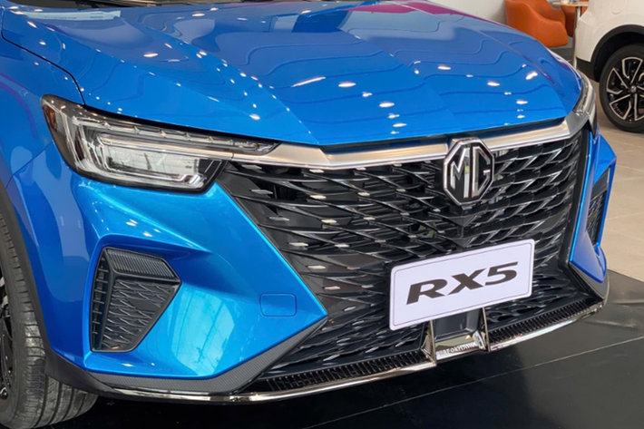 Khu vực đầu xe SUV MG RX5 gây ấn tượng với mặt ca lăng cỡ lớn hình đồng hồ cát, gợi liên tưởng đến Lexus. Cụm đèn pha được bao quanh bởi dải LED định vị ban ngày hình chữ C cách điệu. Trong khi đó, ở phía dưới là hai khe gió cỡ lớn đặt dọc.