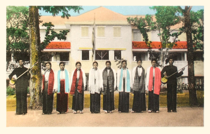 Nhóm thiếu nữ người Thái trắng cùng hai thanh niên chơi đàn tính đứng hai bên.