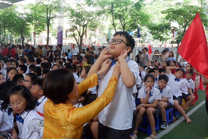 Cô giáo đang chỉnh lại cổ áo cho một học sinh.