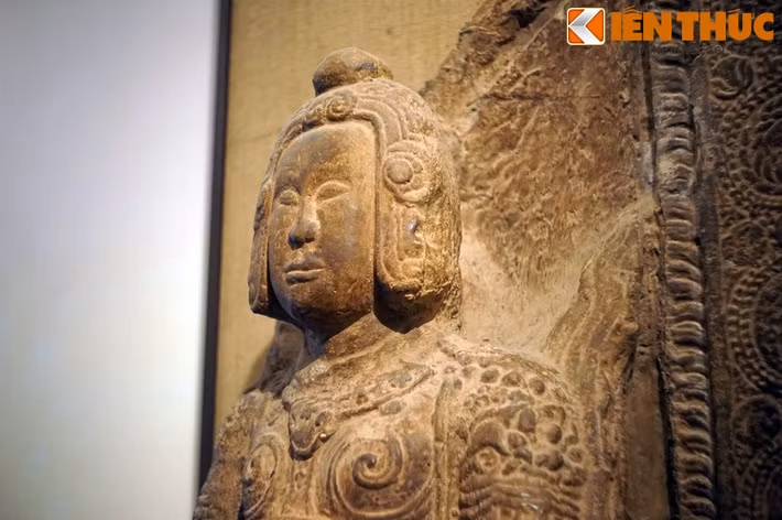 Giữa trán và chóp mũ nổi lên những đường gờ tạo thành hình vòng nối xuống những bông hoa cúc cách điệu hai bên mang tai.