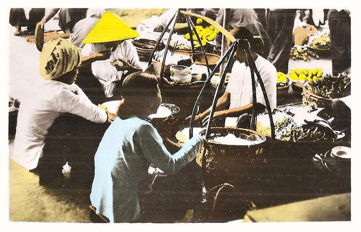 Các bà các cô ghé vào gánh hàng rong vỉa hè để ăn vặt. Ảnh: Public Domain.