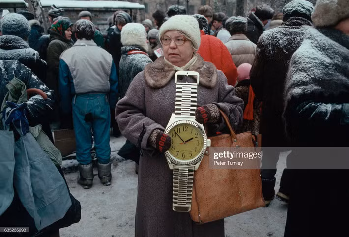 Một cụ bà cố gắng bán chiếc đồng hồ treo tường có hình dáng giống chiếc đồng hồ đeo tay khổng lồ trên con phố đông đúc tuyết phủ ở Moscow, cuối năm 1991, khi sự tồn tại của Liên Xô chỉ còn tính bằng ngày.