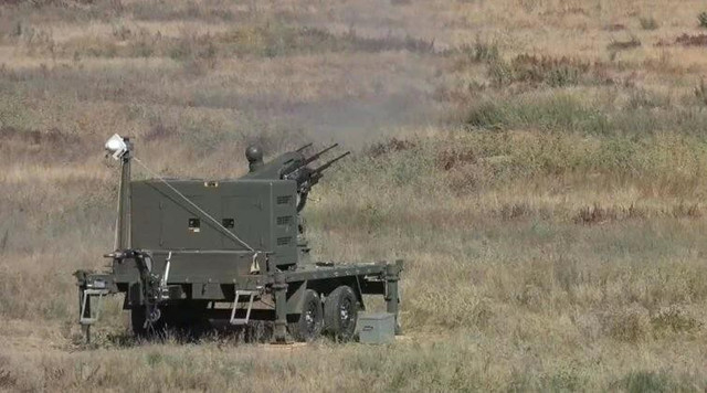 Một hệ thống phòng không tầm gần lắp trên rơ-moóc, trang bị pháo tự động đa nòng, đang triển khai trên thao trường trong một hoạt động huấn luyện/bắn thử nghiệm, thể hiện năng lực đối phó các mối đe dọa đường không tầm thấp như UAV.