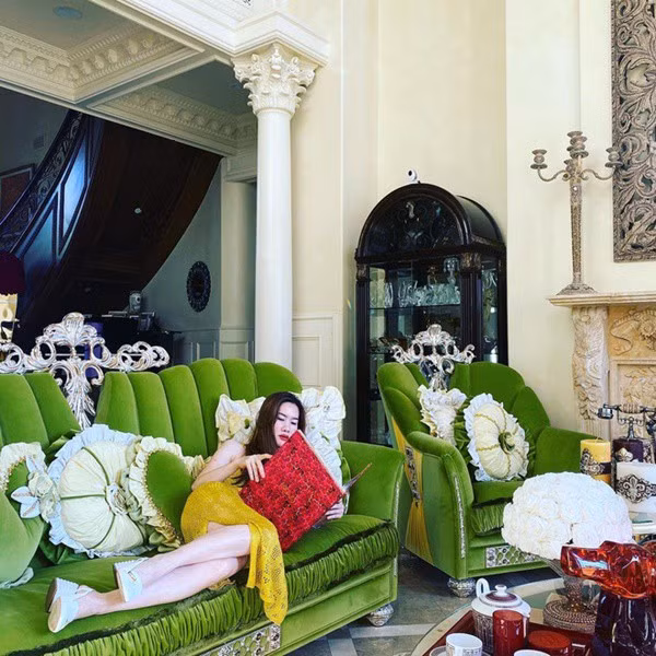 Phòng khách là sự kết hợp của hoa văn chạm trổ tinh tế, sofa màu xanh to, hoa tươi và nhiều món đồ trang trí đính đá quý. Ảnh: Instagram