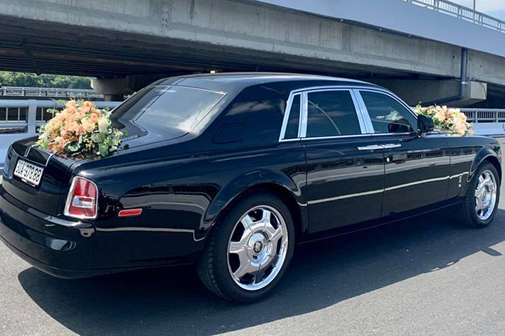 Một mẫu xe siêu sang được sử dụng làm xe cưới là chiếc Rolls-Royce Phantom thế hệ thứ 7 Series I có biển số tam hoa 8. Rolls-Royce luôn là thương hiệu ôtô quý tộc mà đại gia nào cũng muốn sử dụng để làm xe hoa trong ngày trọng đại nhất của con mình. Chính vì thế, việc chiếc Phantom xuất hiện trong đám cưới này cũng là điều không mấy khó hiểu.