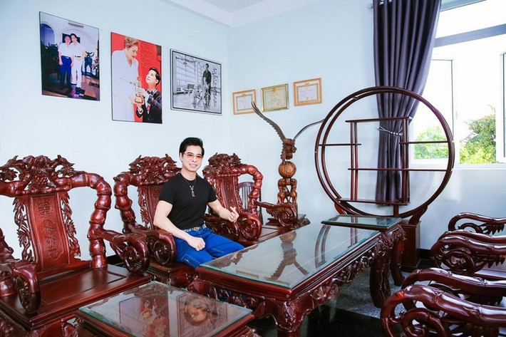 Trong phòng khách kê bộ bàn ghế gỗ đồ sộ, chạm khắc tỉ mỉ.