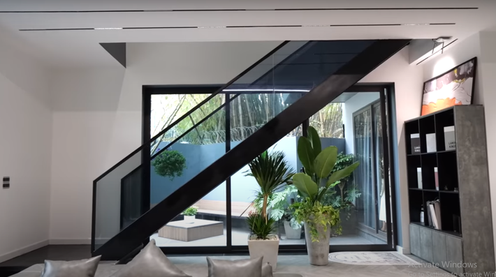 Dẫn lên tầng 2 là cầu thang khung thép màu đen, lan can kính.